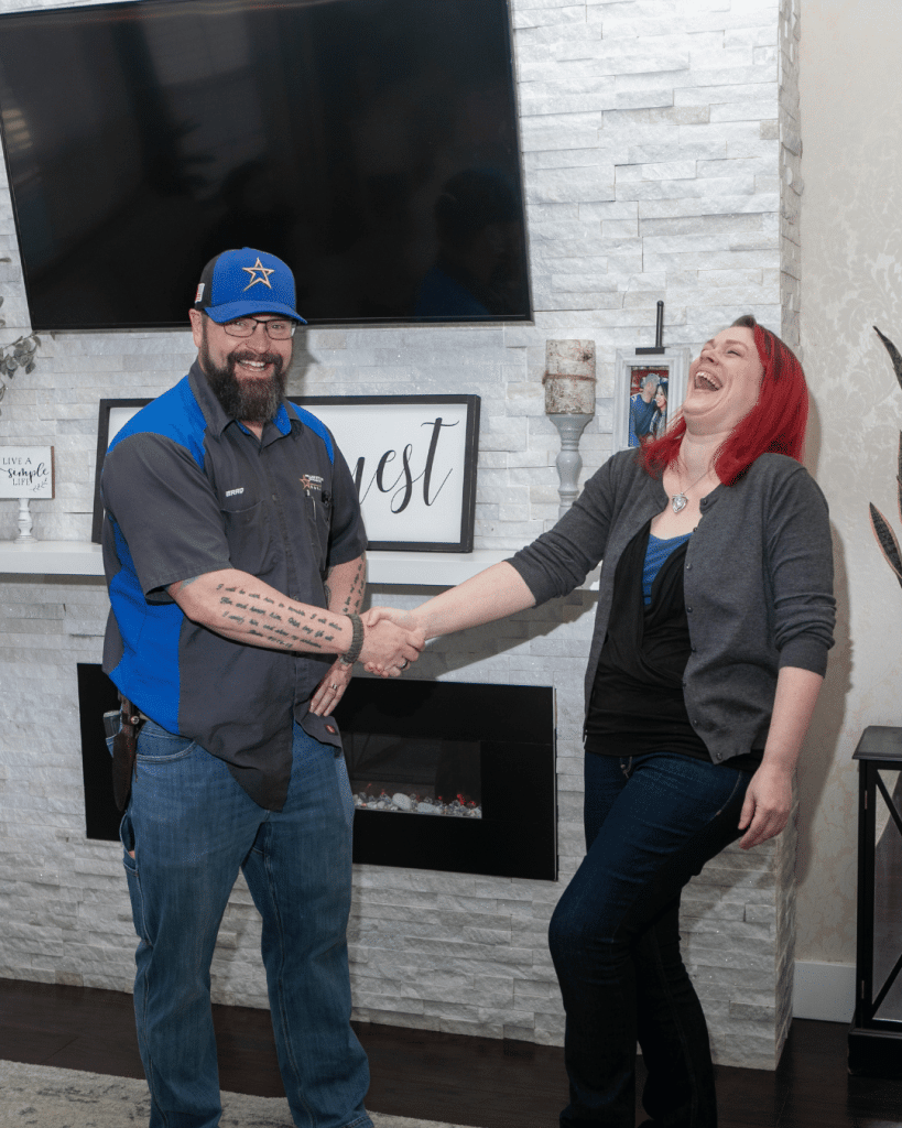 An HVAC technician shakes a woman's hand.