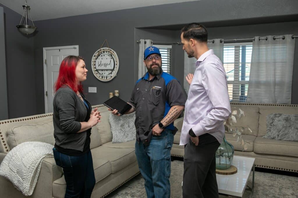 A man, woman, and technician having a conversation in the living room.